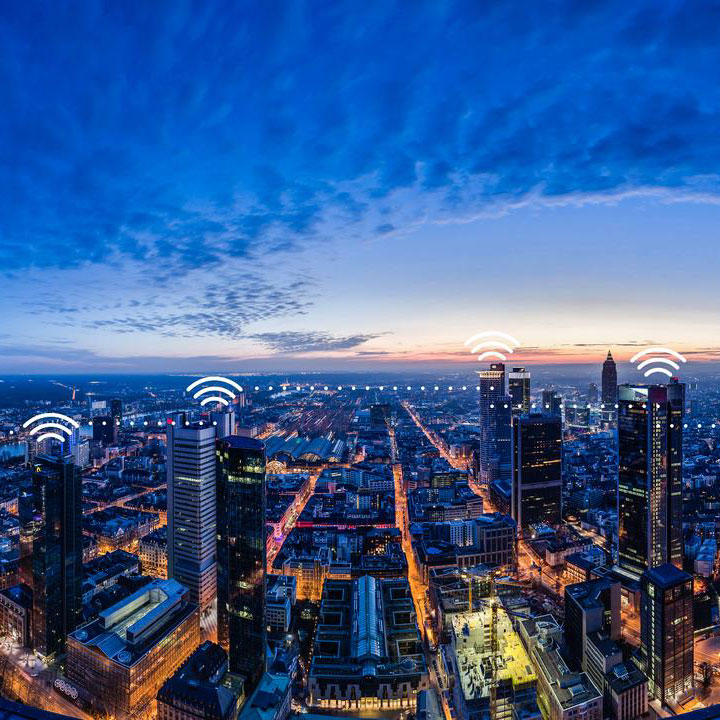 Panorama einer vernetzten Stadt in der Abenddämmerung mit WLAN-Symbolen über Gebäuden als Symbol für IoT-Konnektivität