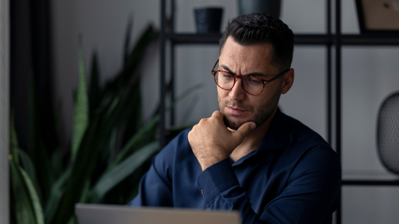 Nachdenklicher Geschäftsmann schaut auf Laptop