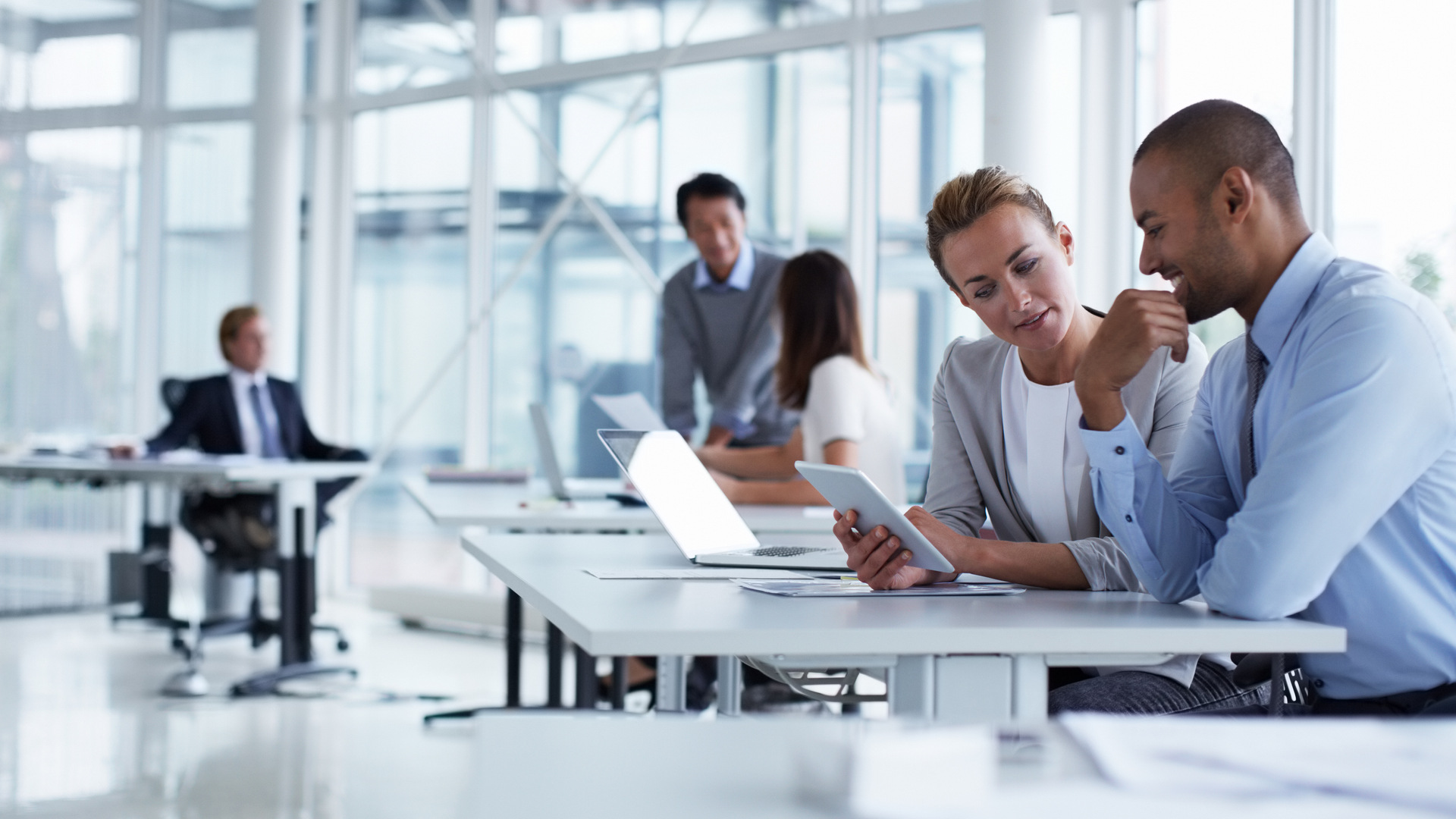 Teammitglieder mit Tablets und Laptops arbeiten und diskutieren in einem Büro