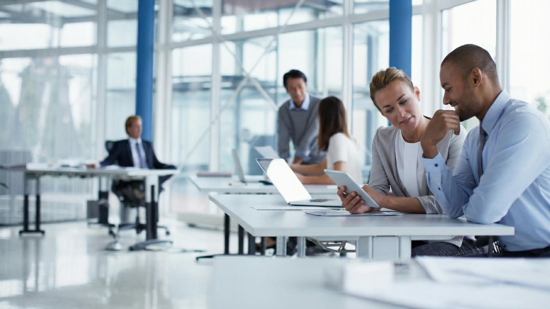 Teammitglieder mit Tablets und Laptops arbeiten und diskutieren in einem Büro