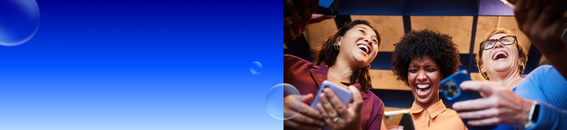 Abbildung: Drei Frauen stehen zusammen, halten alle ein Smartphone in der Hand und lachen