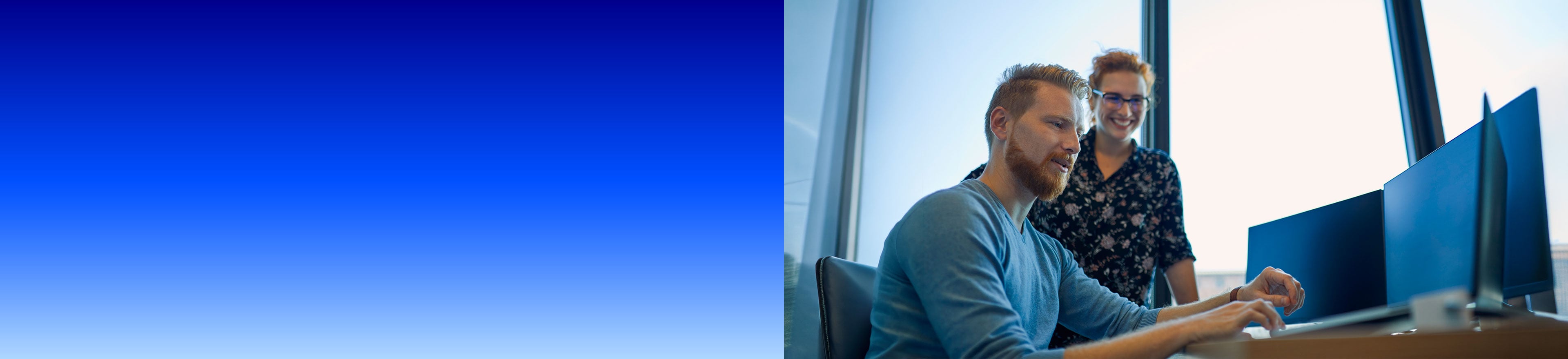 Zwei Kollegen arbeiten gemeinsam an einem Bildschirmarbeitsplatz mit zwei Monitoren in einem hellen Büro, links blauer Farbverlauf.