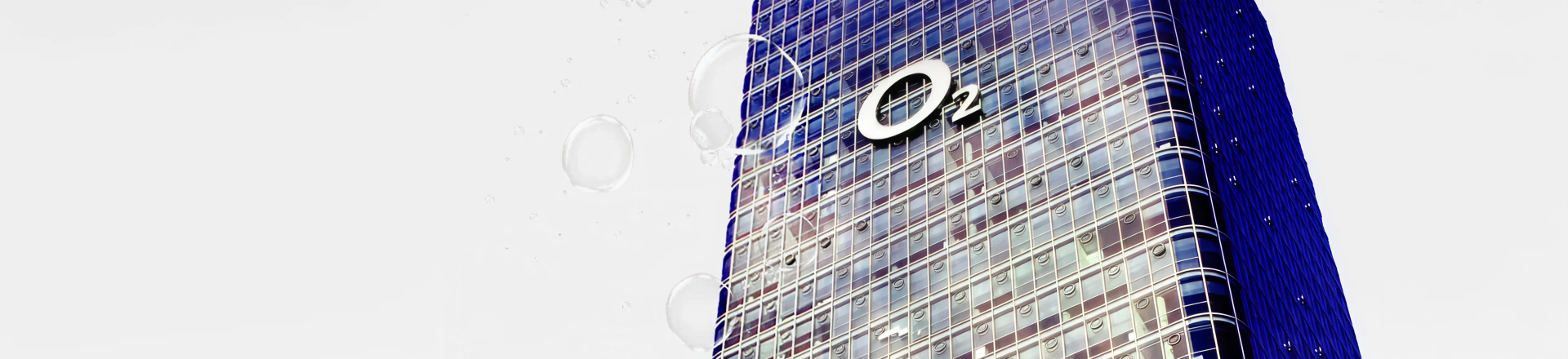 Modernes Glasgebäude mit o2 Logo vor hellem Hintergrund und schwebenden Luftblasen.